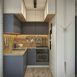 Compact kitchen with grey and white cabinets and a wooden worktop